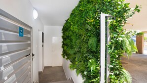 Een gang met een verticale tuinwand, een deur met een bordje en een trap.