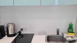 Μια κουζίνα με νεροχ ύτη, βραστήρα, πλυντήριο πιάτων και ένα πράσινο μπουκάλι με υγρό πιάτων.