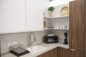 Uma cozinha moderna com pia, micro-ondas e cafeteira.