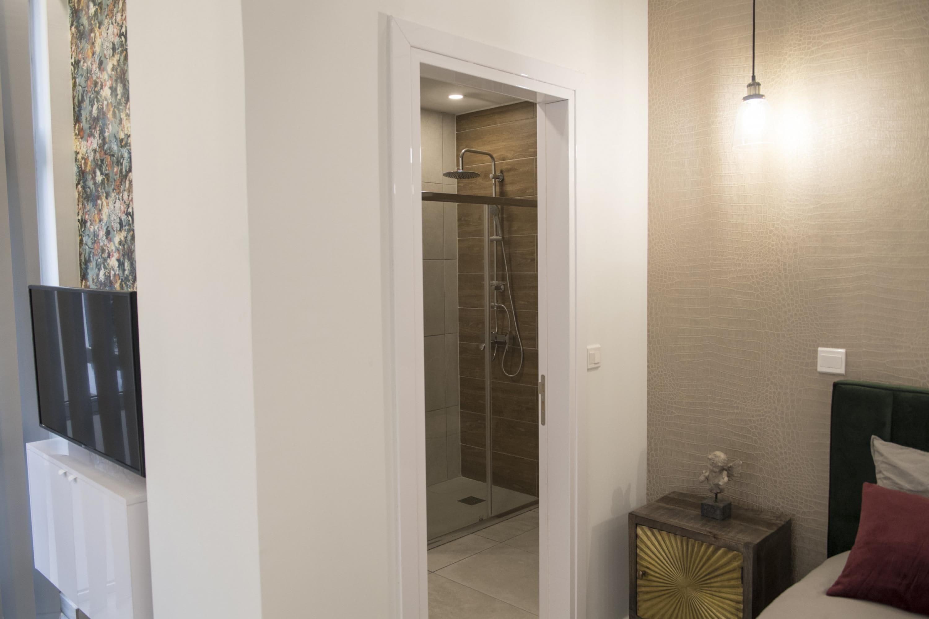 A hotel room with a shower, a bedside table, and a bed with a green headboard.