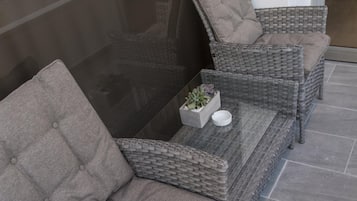 A wicker sofa set with a glass-top coffee table, a small potted plant, and a white bowl.