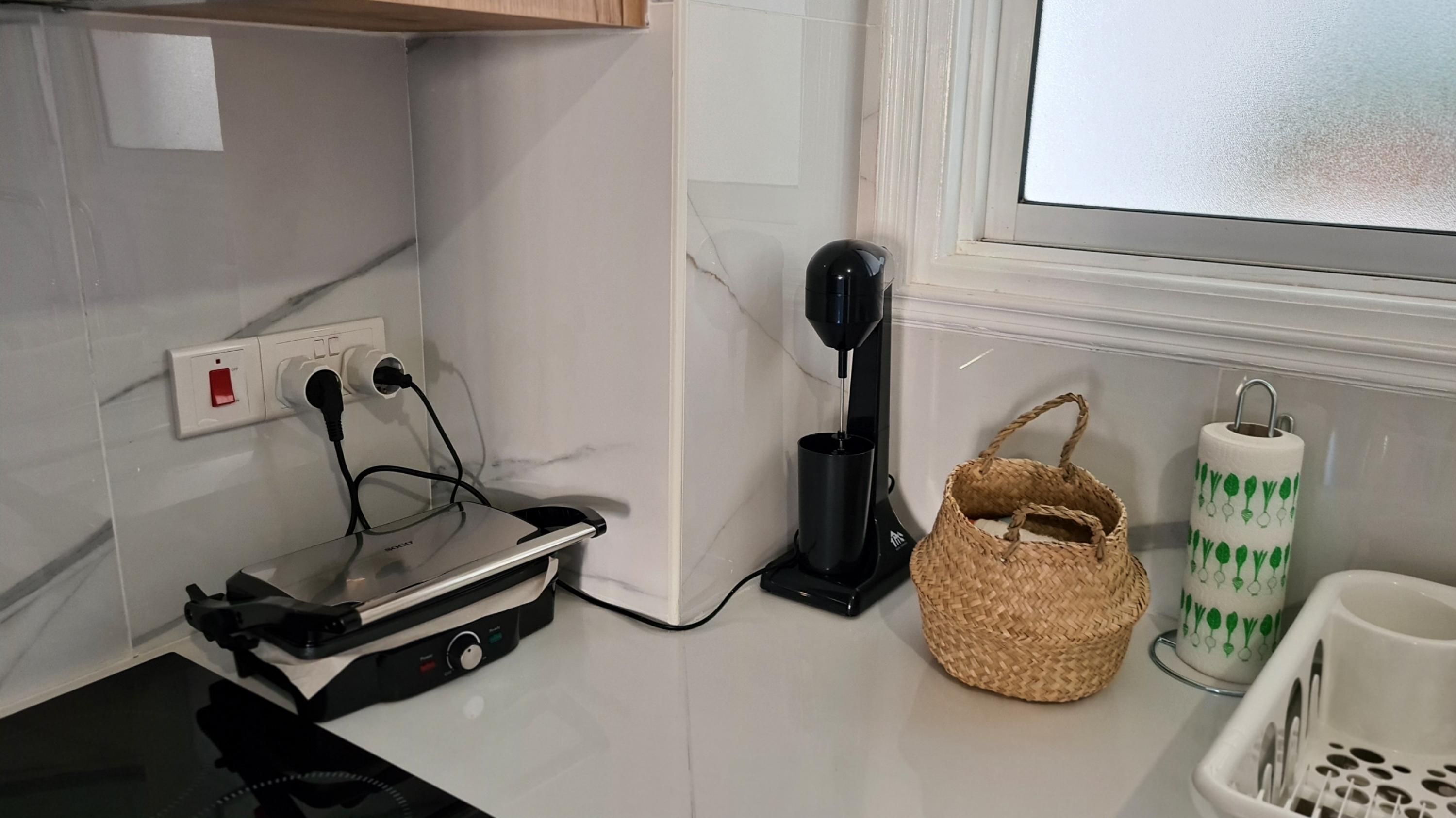 A kitchen with a coffee maker, a portable heater, a woven basket, and a paper towel holder.