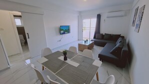 Una sala de estar moderna con comedor, un sofá y un televisor montado en la pared.