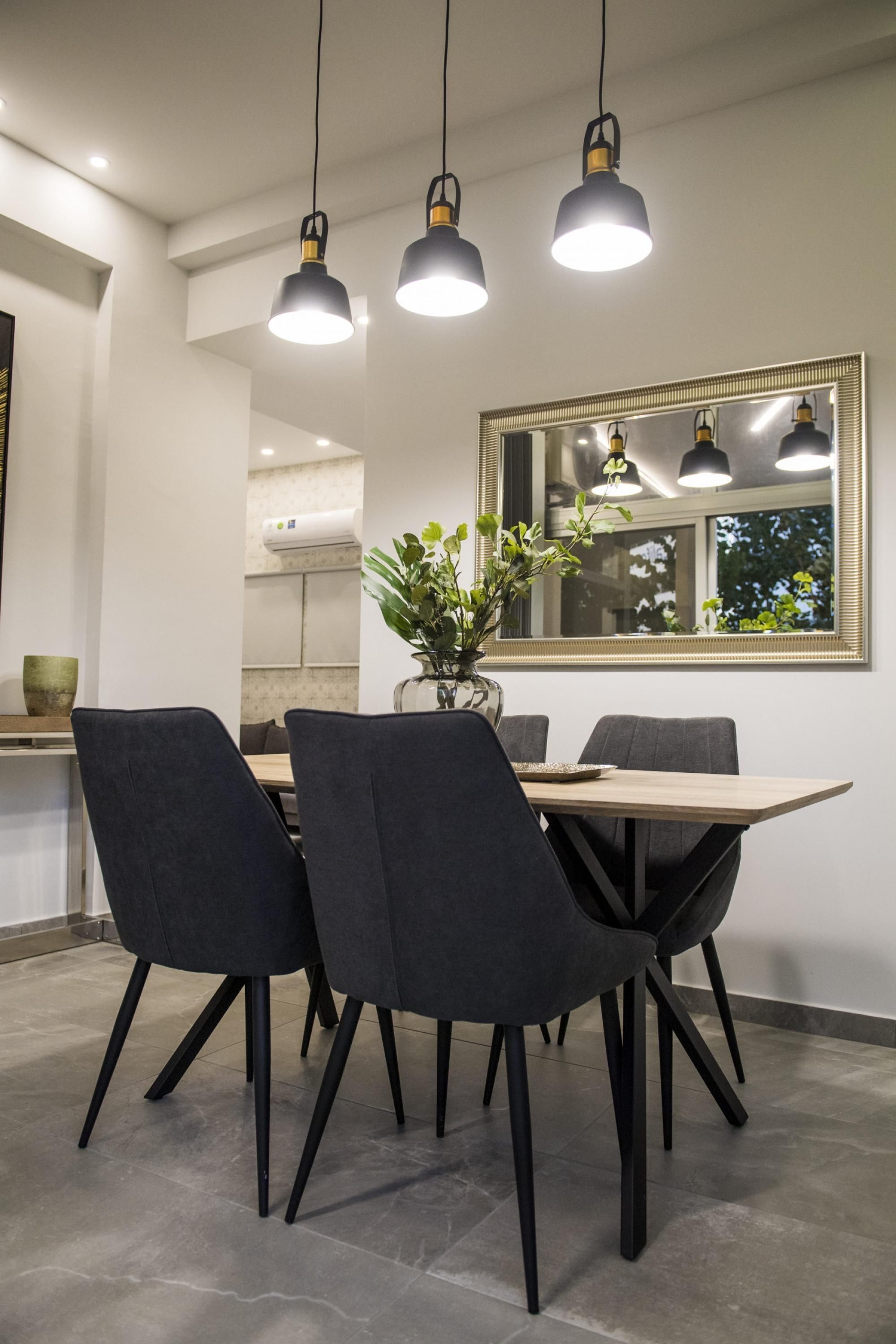 Un comedor con una mesa de madera, cuatro sillas y lámparas colgantes.