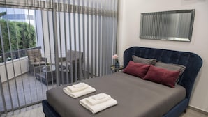 Ein Schlafzimmer mit einem großen Bett, einem Nachttisch, einem Spiegel und Blick auf den Balkon.