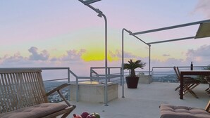 A terrace with a table set for dining, a potted plant, and a view of the sea at sunset. - 95 TLA - Stay Sunset Palazzo (Tala)