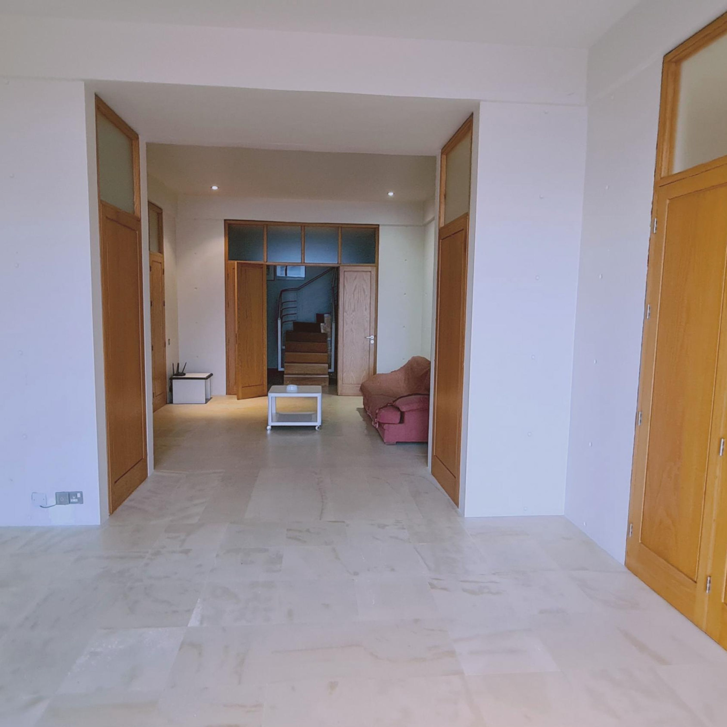 A spacious hallway with a tiled floor, a small table, and a sofa.