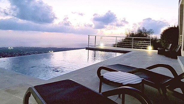 An infinity pool with a view of the city skyline, outdoor furniture, and a railing. - 95 TLA - Stay Sunset Palazzo (Tala)