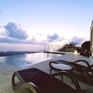 An infinity pool with a view of the city skyline, outdoor furniture, and a railing. - 95 TLA - Stay Sunset Palazzo (Tala)
