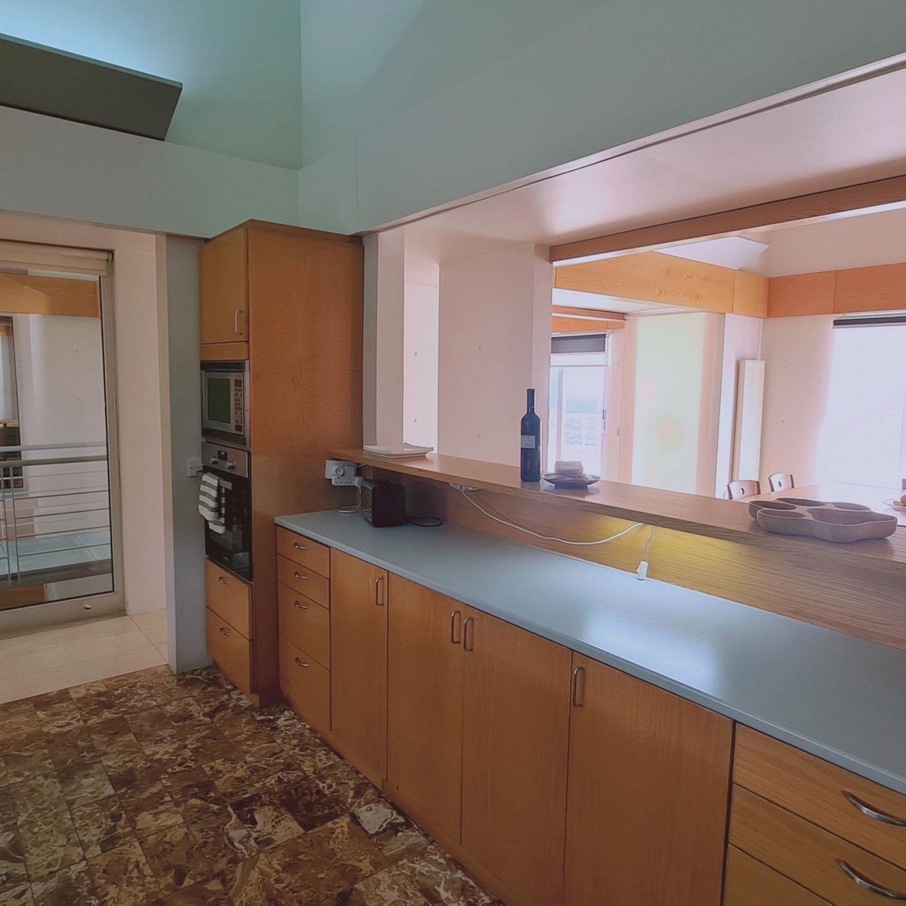 A kitchen with wooden cabinets, a countertop, and a large mirror.