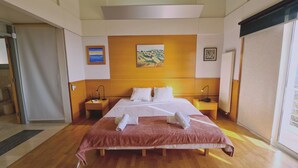 A hotel room with a large bed, two bedside tables, a painting on the wall, and a window. - 95 TLA - Stay Sunset Palazzo (Tala)