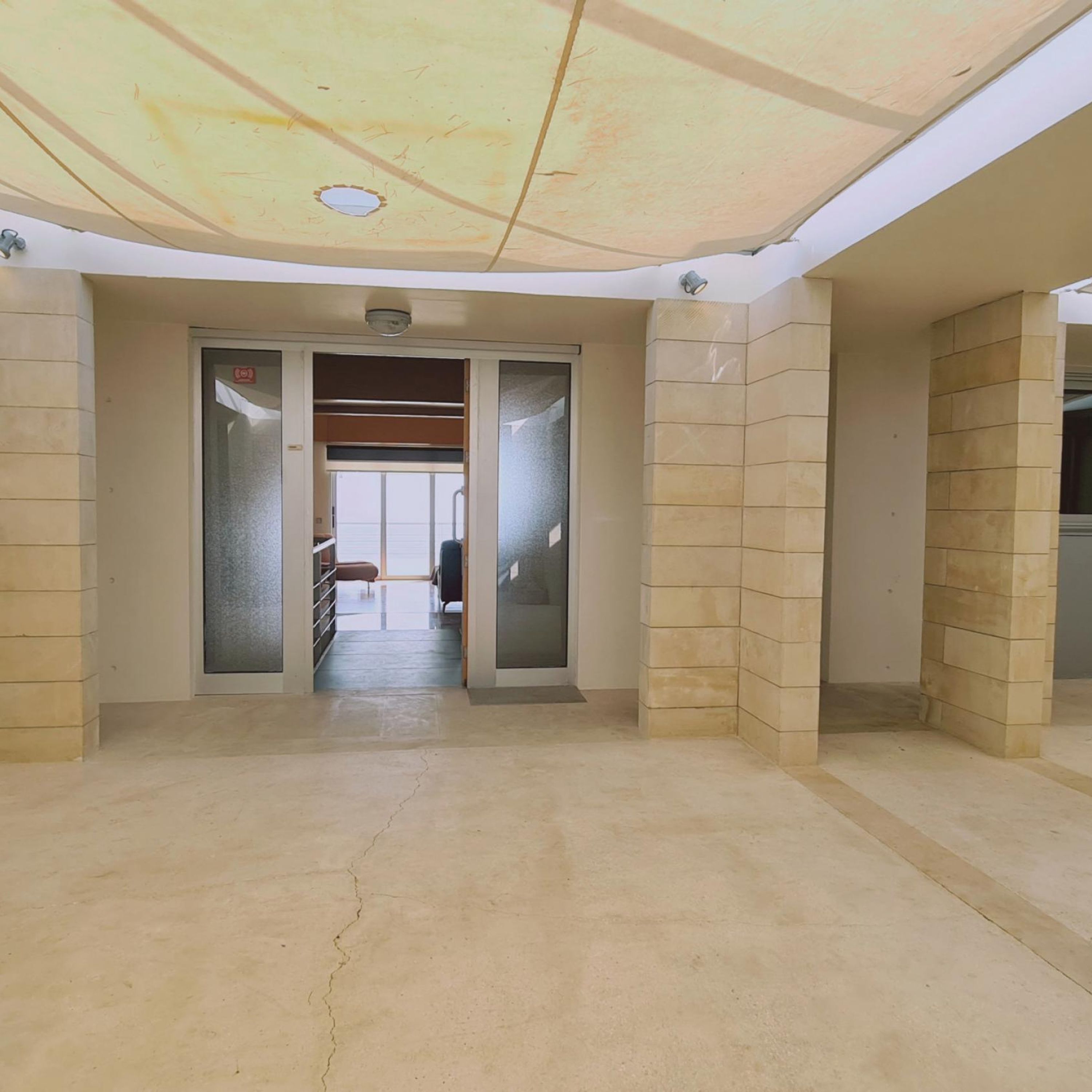 A hallway with a tiled floor and a ceiling with a skylight.