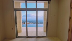 A room with a large sliding glass door leading to an outdoor swimming pool and a cityscape view. - 95 TLA - Stay Sunset Palazzo (Tala)
