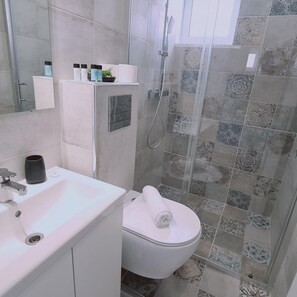 Un baño con lavamanos blanco, inodoro y cabina de ducha.