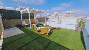 A rooftop terrace with artificial grass, wooden furniture, and a pergola. - 84 AN 1 - Stay Napa Aura Apartment (Ayia Napa)