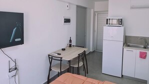A compact room with a bed, a small table, a television, a microwave, and a sink. - 100 AN - Napa Living 23 (Ayia Napa)
