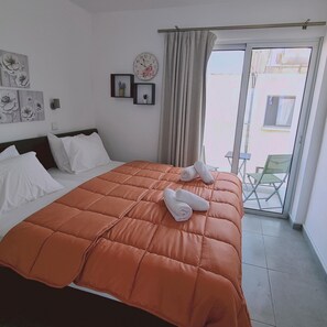 Una camera d'albergo con un letto grande, vista all'esterno e una sveglia appesa al muro.