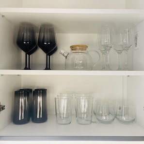 A shelf with various glassware, including wine glasses and tumblers.