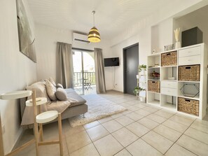 A modern living room with a sofa, a coffee table, a TV, and a bookshelf. - 91 KPF - Stay Artifex Apartment (Paphos)