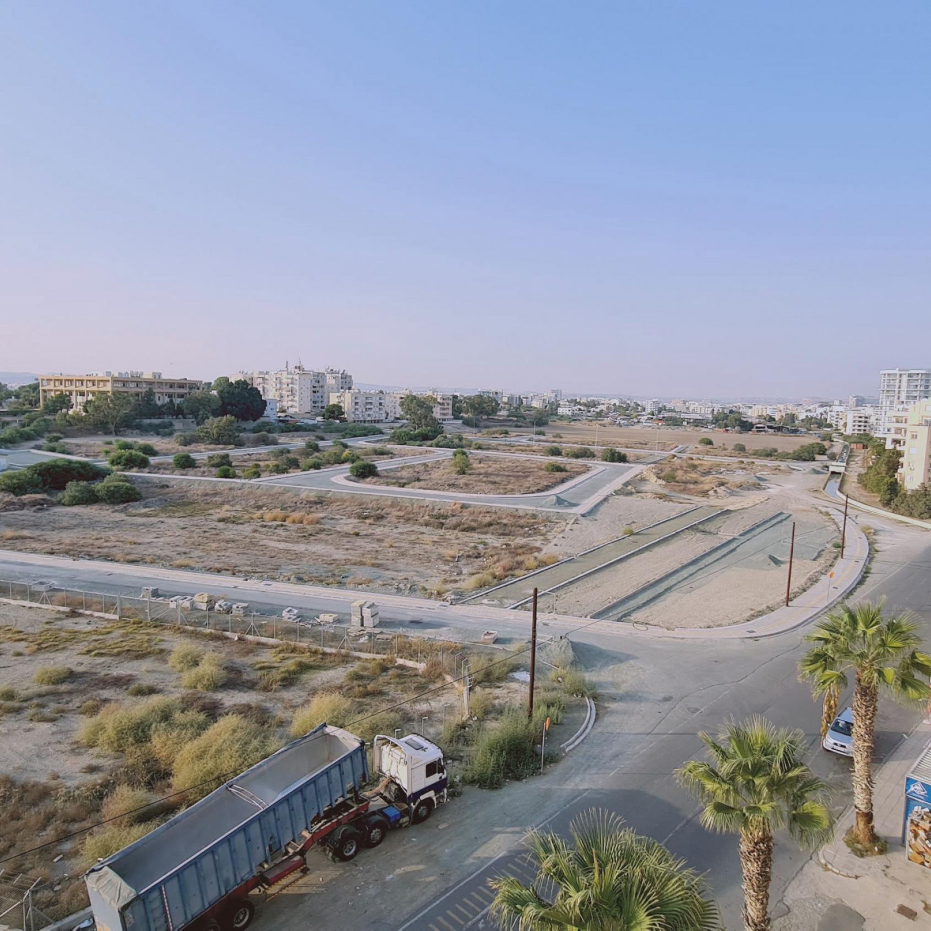 Luchtbeeld van een stadsgezicht met een weg, een vrachtwagen en gebouwen op de achtergrond.