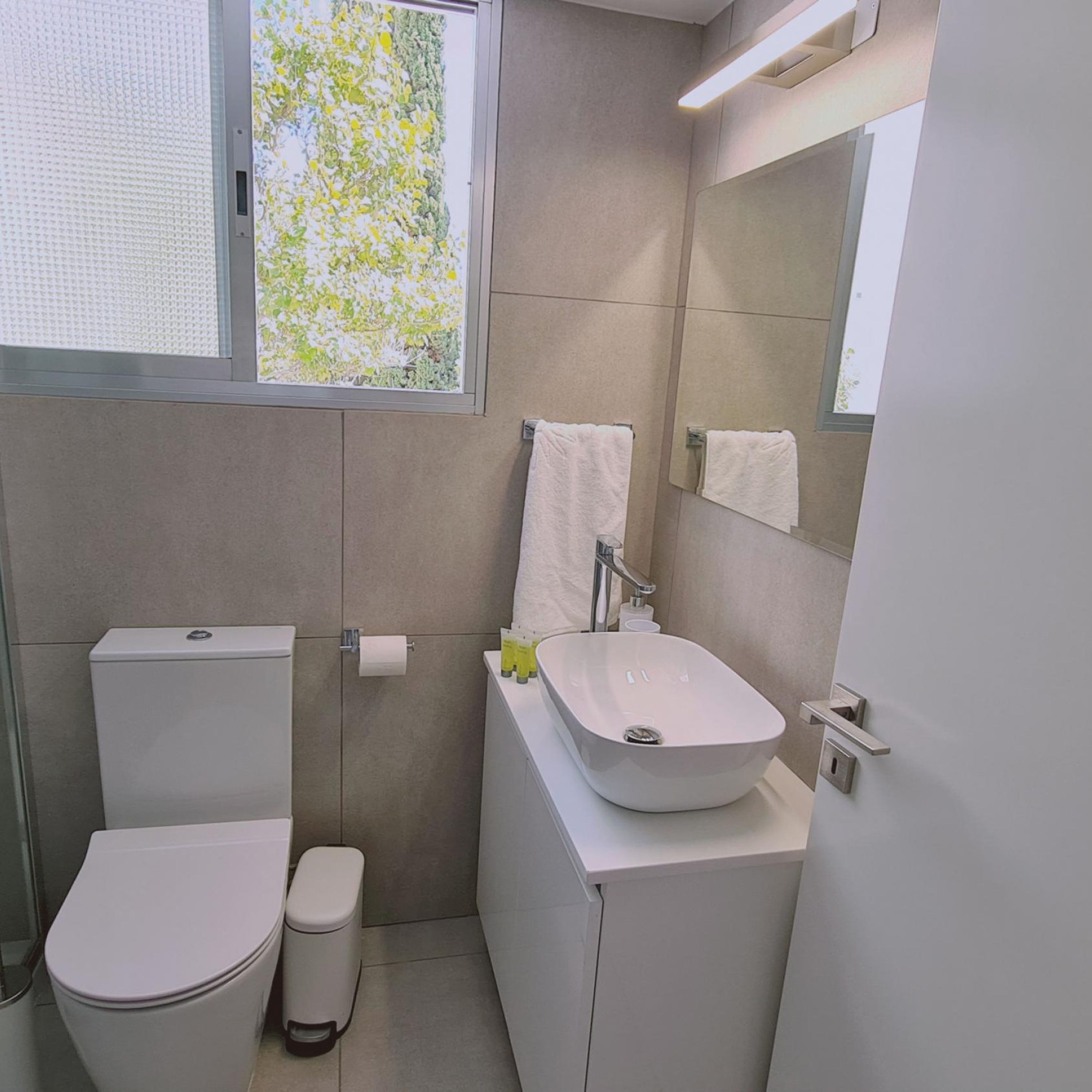 A modern bathroom with a toilet, sink, and mirror.