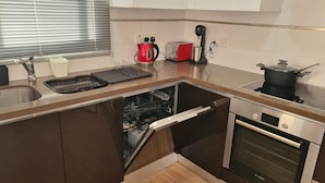 Une cuisine compacte équipée d’un lave-vaisselle, d’un four, d’une bouilloire, d’un grille-pain et d’une casserole sur la cuisinière.
