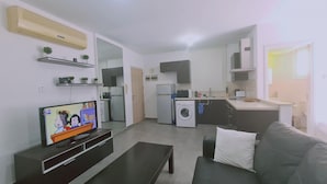 A compact living space with a TV, sofa, and kitchenette. - 17 MAK - Stay Universal Studio (Egkomi)