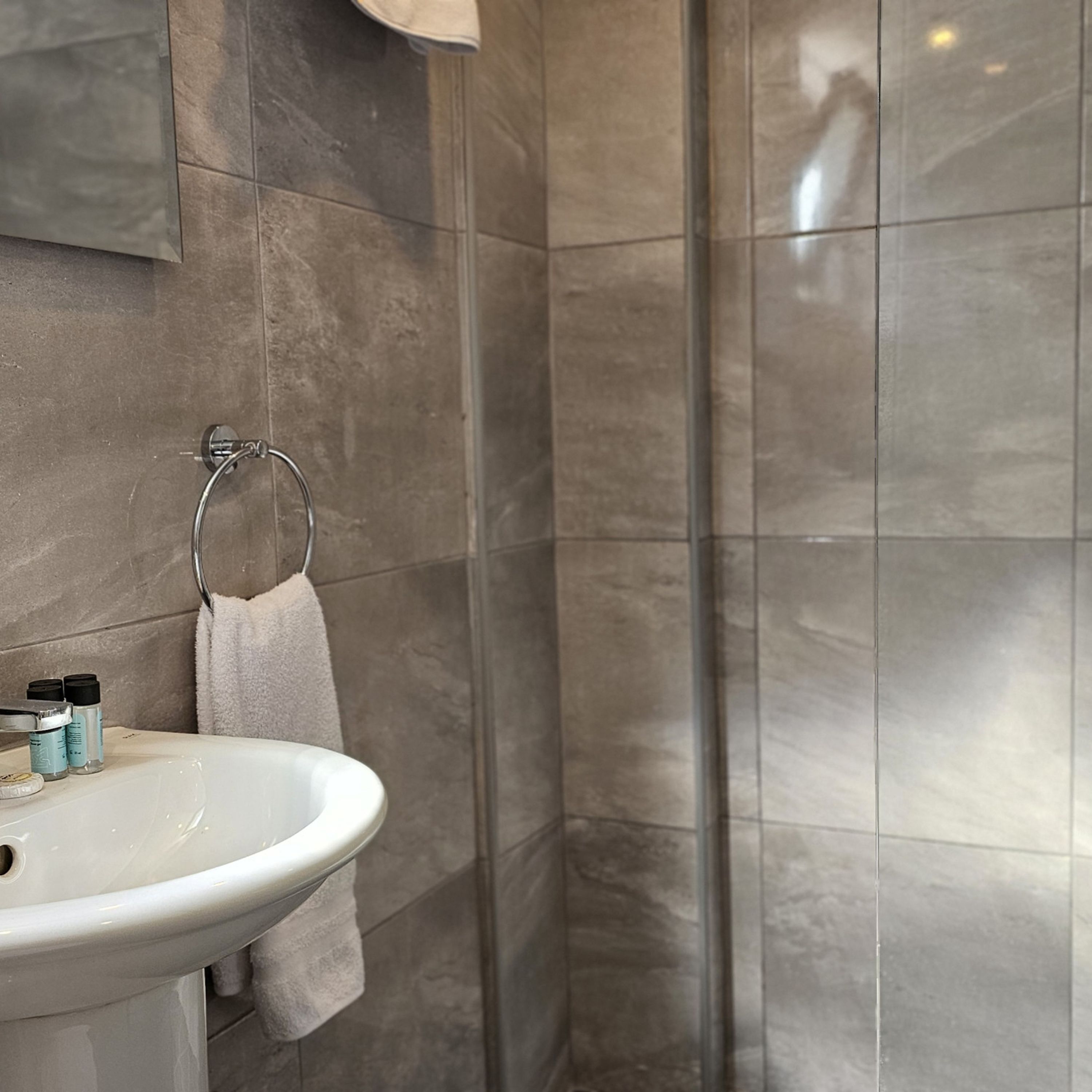 A bathroom with a white sink, a towel hanging on a rack, and a glass shower enclosure.