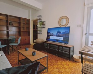 A living room with a television, wooden furniture, a bookshelf, and a window. - 19 LCA - Stay Antique Apartment (Larnaca)