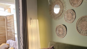 A cozy living room with a green sofa, multiple cushions, and decorative woven wall hangings. - 103 LCA - Stay Green Apartment (Larnaca)