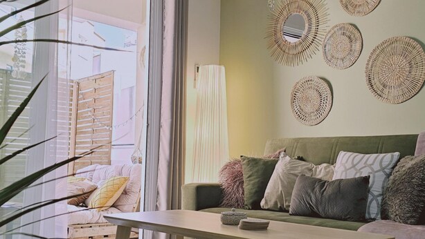 A living room with a green sofa, a wooden coffee table, and a large woven lamp. - 103 LCA - Stay Green Apartment (Larnaca)