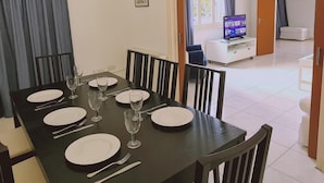 A dining area with a table set for six, chairs, a television in the background, and a view of the living area. - 75 NIC - Stay Mythos Down Town House (Nicosia)