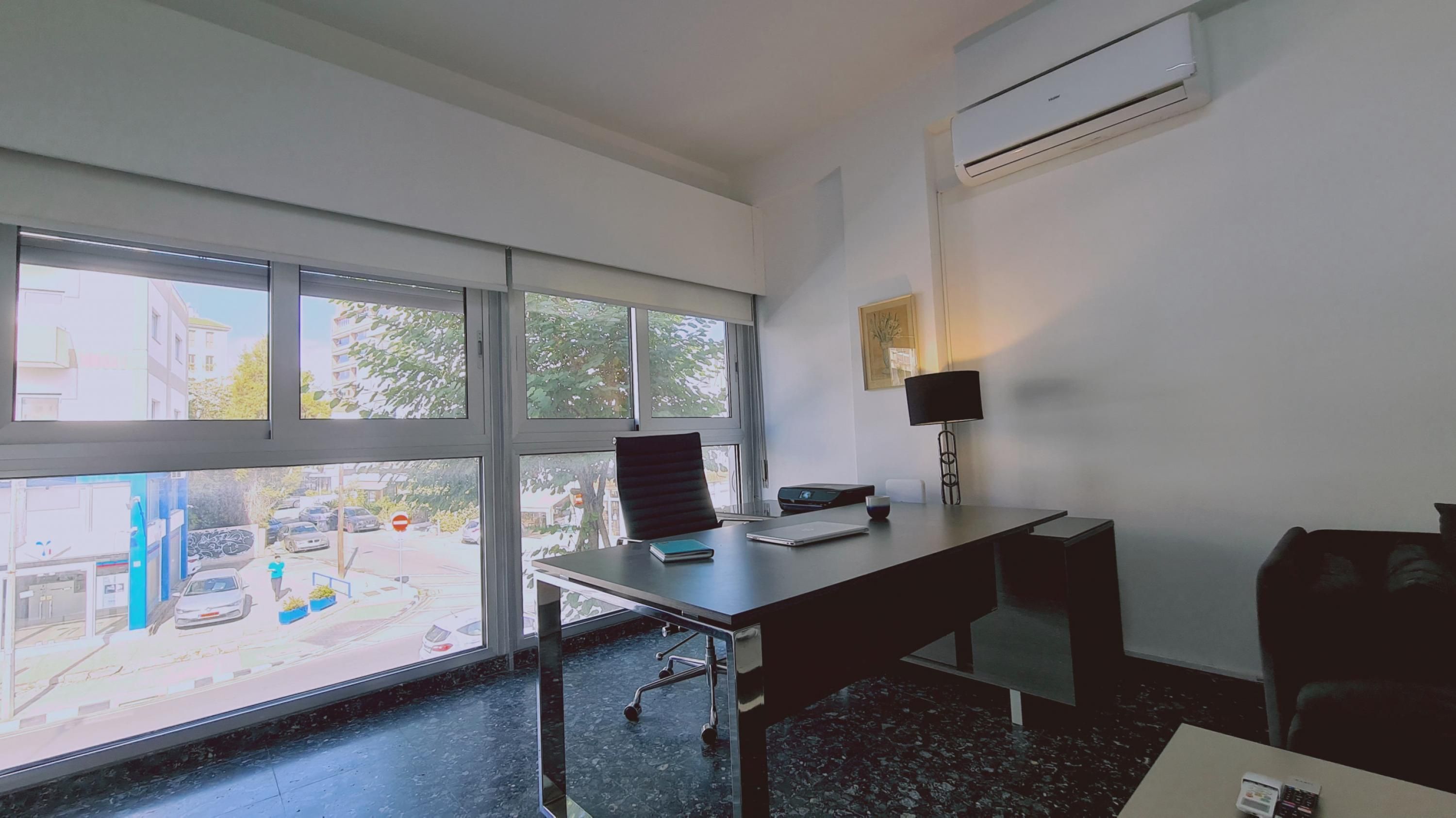 A modern office space with a desk, chair, laptop, and a lamp.