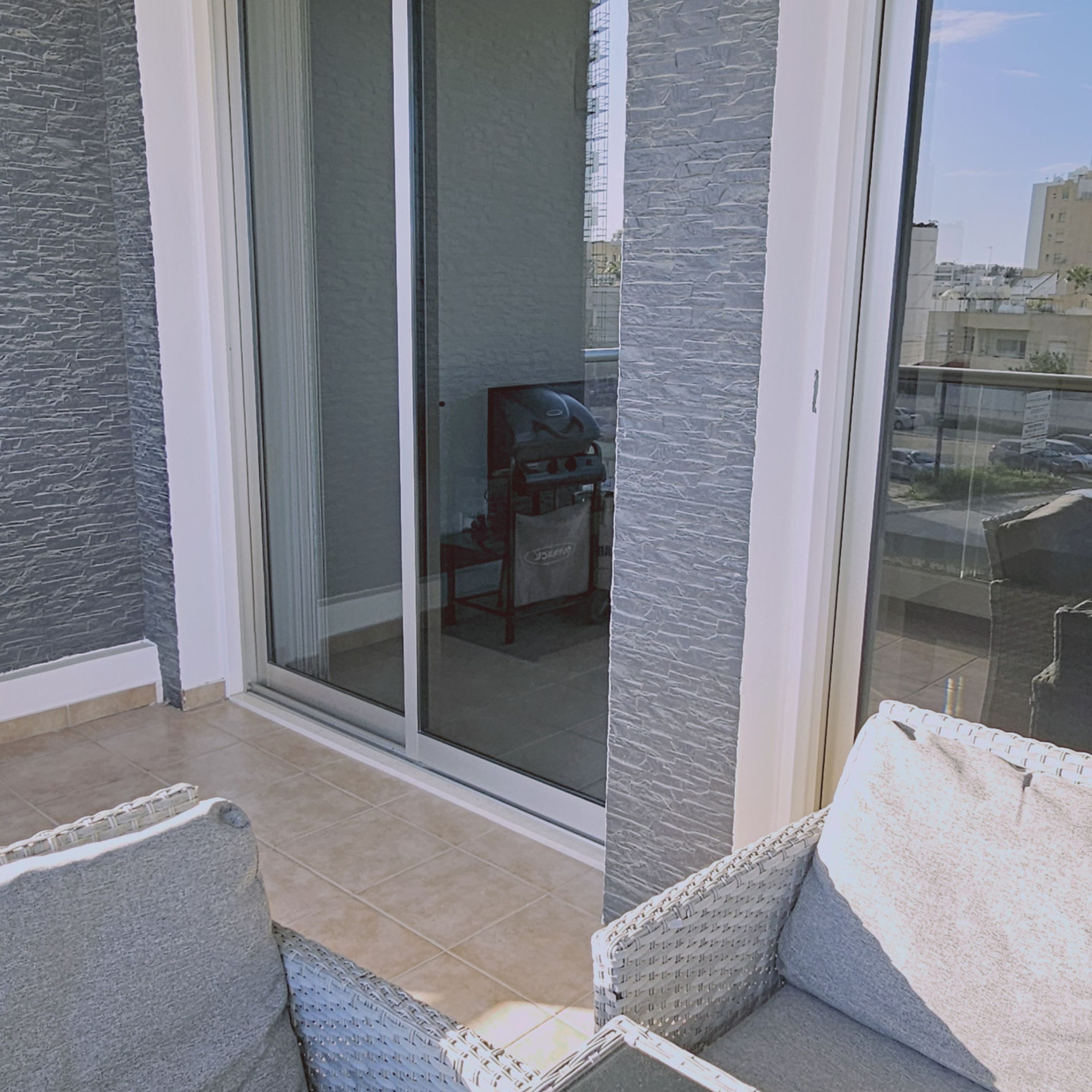 A balcony with a sliding glass door, a chair, and a view of a building in the background.