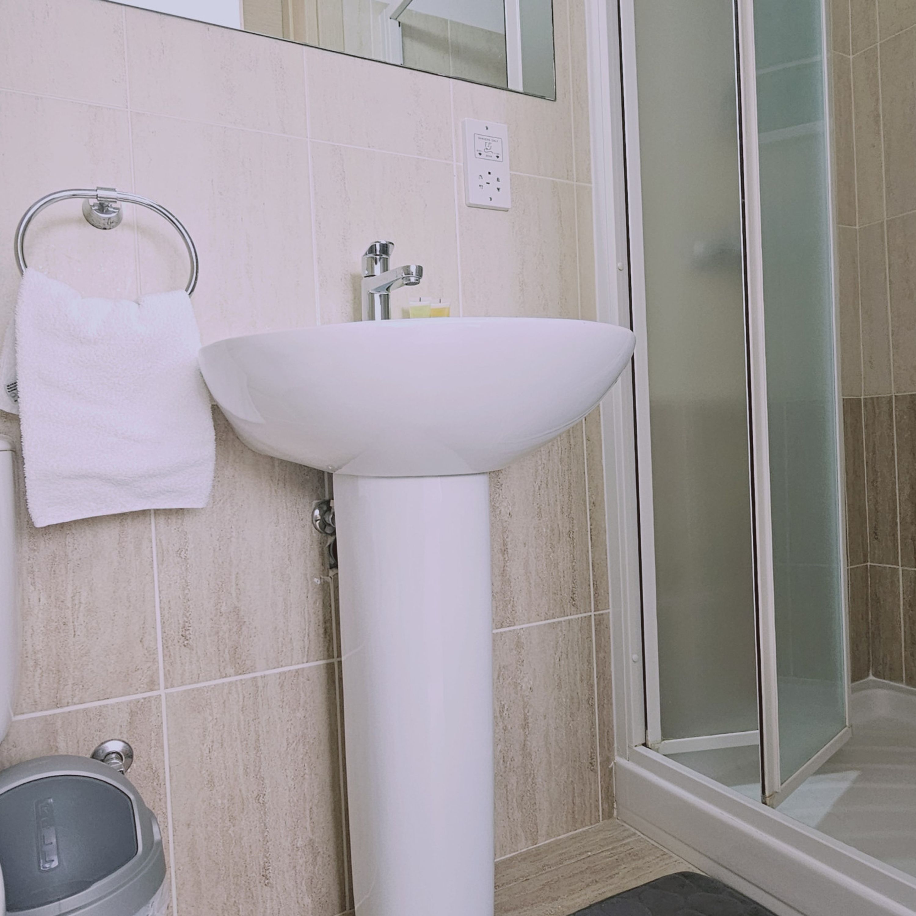 A bathroom with a white sink, a towel rack, and a shower area.