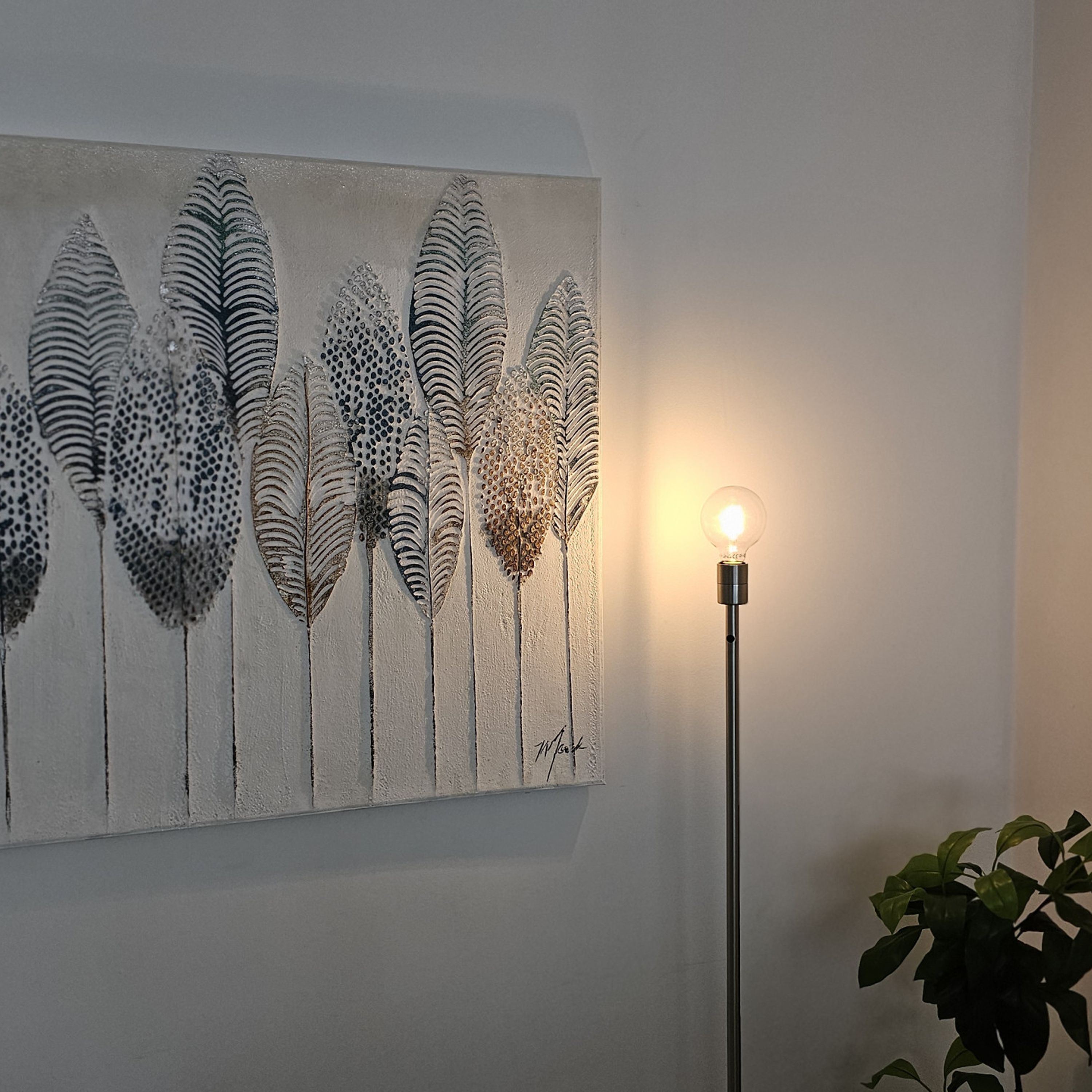 Un mur orné d’une œuvre d’art texturée représentant des feuilles stylisées et un lampadaire avec une ampoule.