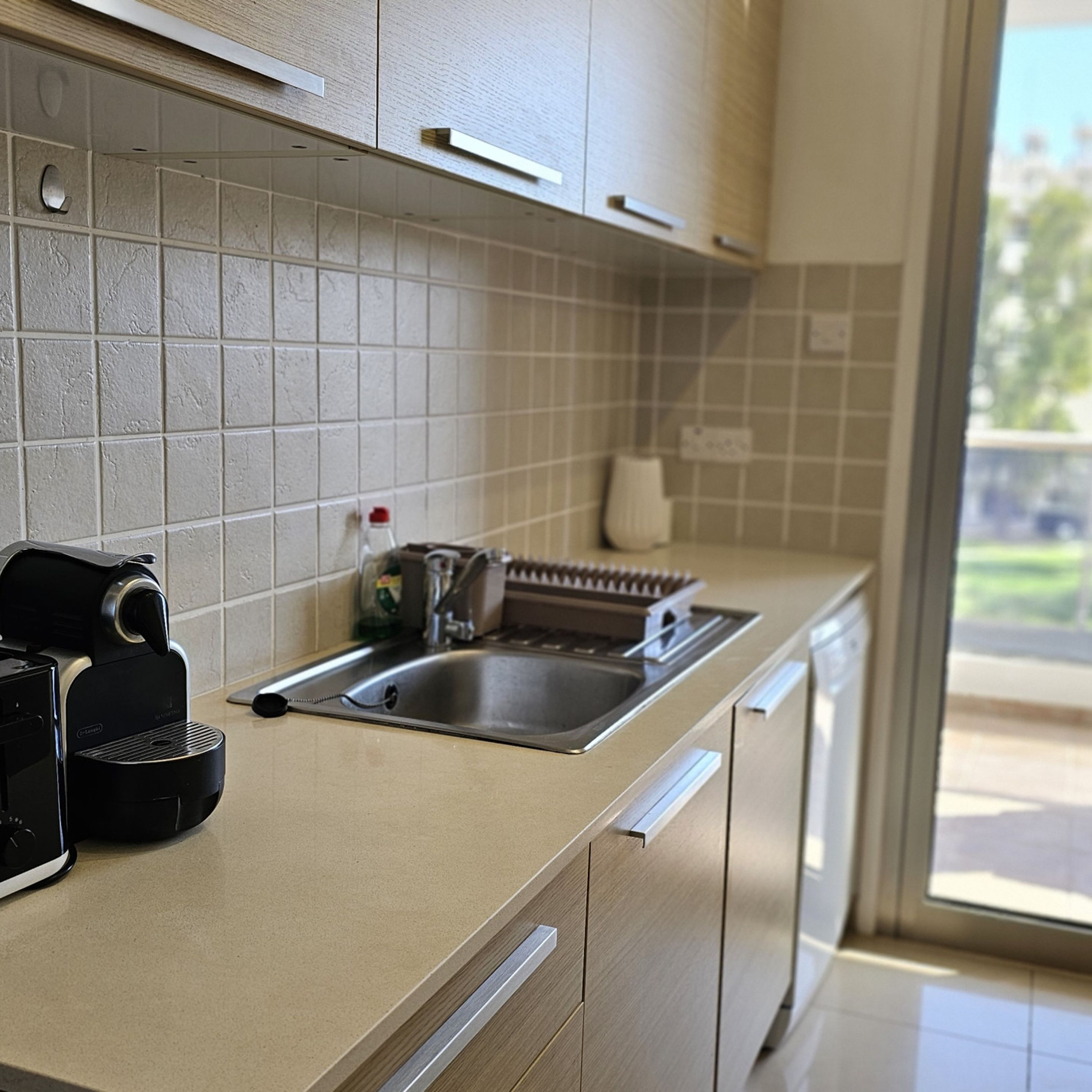 Una cucina moderna dotata di lavastoviglie, macchina del caffè e lavello.