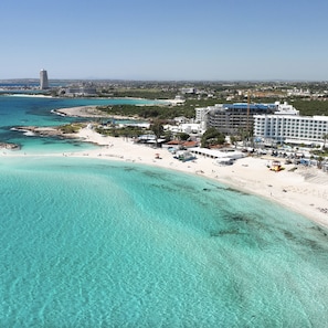 A coastal resort with a beachfront, a tall tower in the background, and a large hotel building. - 116 AN - Stay Nissi Blossom Apartment (Ayia Napa)