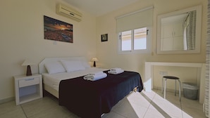 A hotel room with a bed, bedside tables, a window, a mirror, and a picture on the wall. - 116 AN - Stay Nissi Blossom Apartment (Ayia Napa)