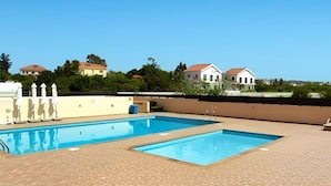 A rooftop swimming pool with two separate sections, surrounded by a brick deck and white umbrellas. - 116 AN - Stay Nissi Blossom Apartment (Ayia Napa)