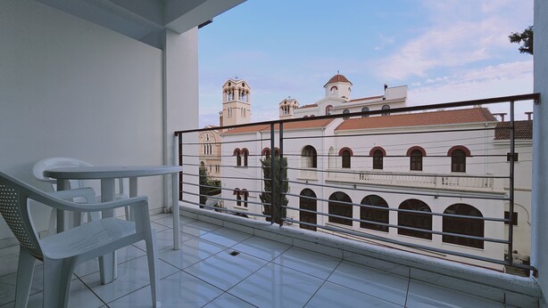 A balcony with a view of a historic building with arched windows and a red-tiled roof. - 109 LIM 1 - Stay Olive Studio (Limassol)