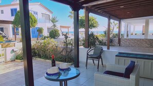 A covered outdoor seating area with a table, chairs, and a bottle of wine. - 10 MEN - Stay Crystal Waves Maisonette (Meneou)
