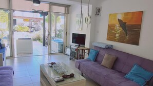 A living room with a purple sofa, a glass coffee table, and a television. - 10 MEN - Stay Crystal Waves Maisonette (Meneou)
