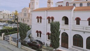 A white building with arched windows and a bell tower, surrounded by trees and a street. - 109 LIM 3 - Stay Terra Cota Studio (Limassol)