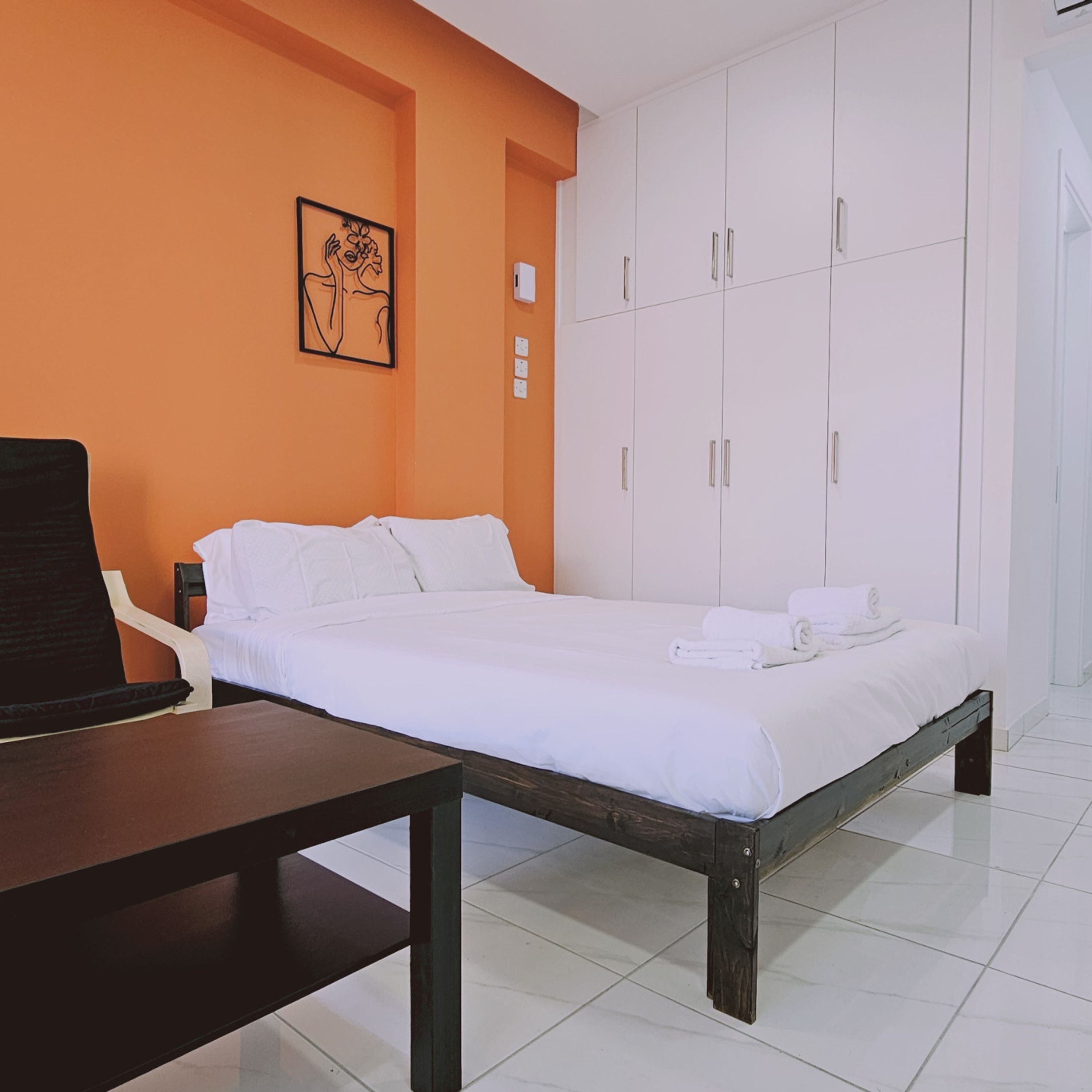 A hotel room with a bed, a chair, a desk, and a wardrobe.