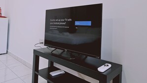 A flat-screen TV on a black stand with a remote control on top. - 109 LIM 3 - Stay Terra Cota Studio (Limassol)