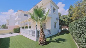 A two-story house with a white exterior, a balcony, and a well-maintained lawn.