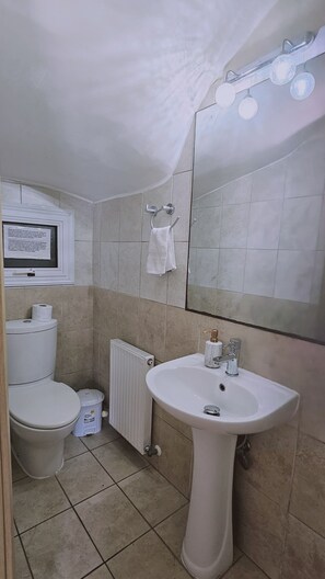 Un baño con lavamanos blanco, inodoro y espejo con iluminación.