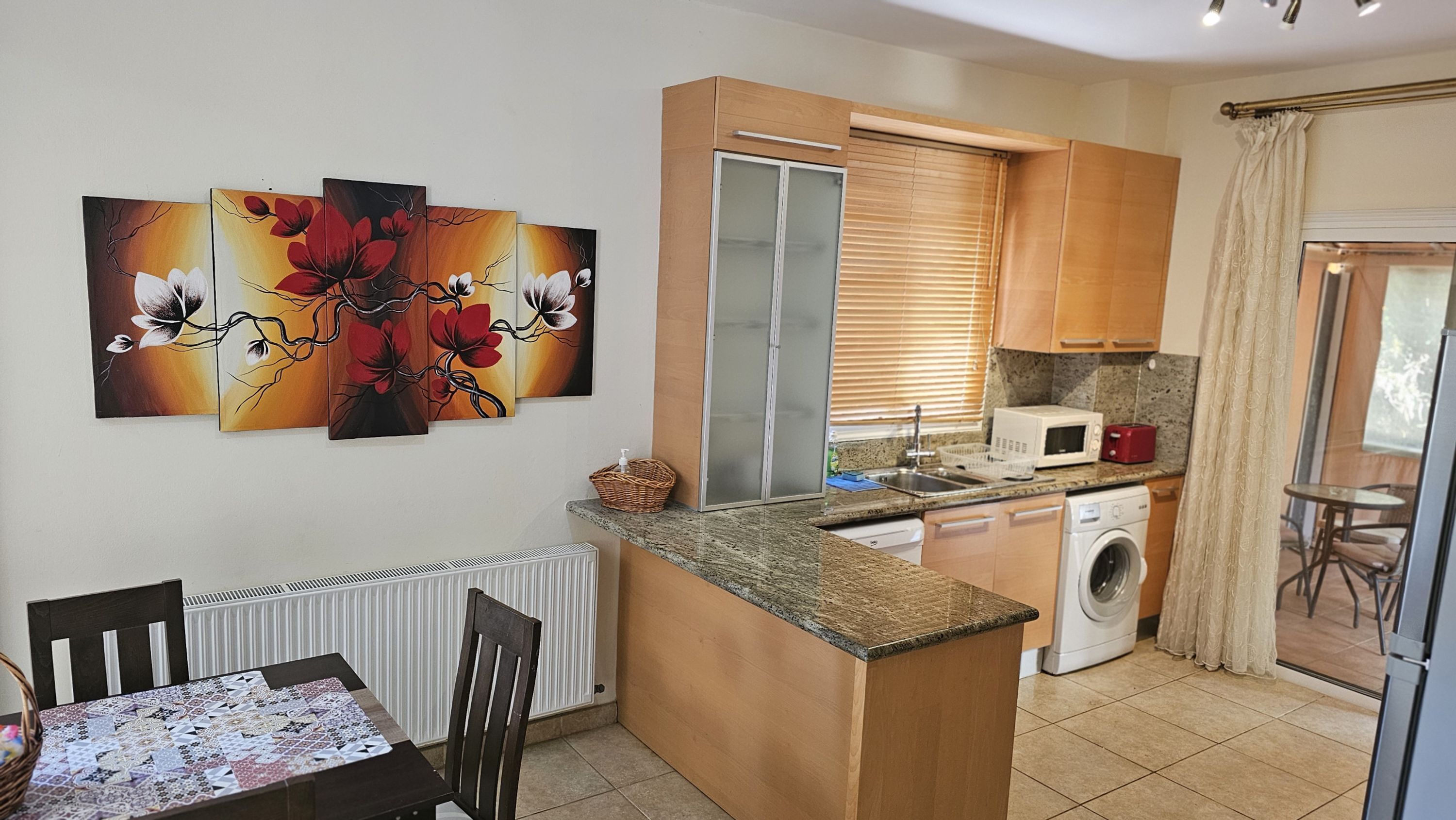 A compact kitchen with a built-in microwave, a washing machine, and a dining area with a table and chairs.