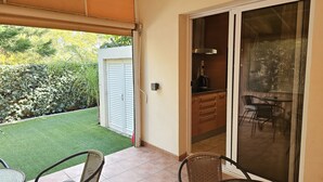 Un patio con puerta corrediza de vidrio que da a una cocina, una pequeña mesa de comedor y sillas.